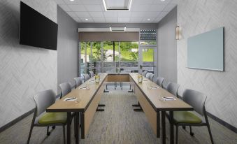 a conference room with long tables and chairs , a tv on the wall , and large windows at SpringHill Suites Tuckahoe Westchester County