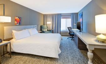 a modern hotel room with a large bed , white sheets , and a comfortable seating area at Hilton Garden Inn Chesterton