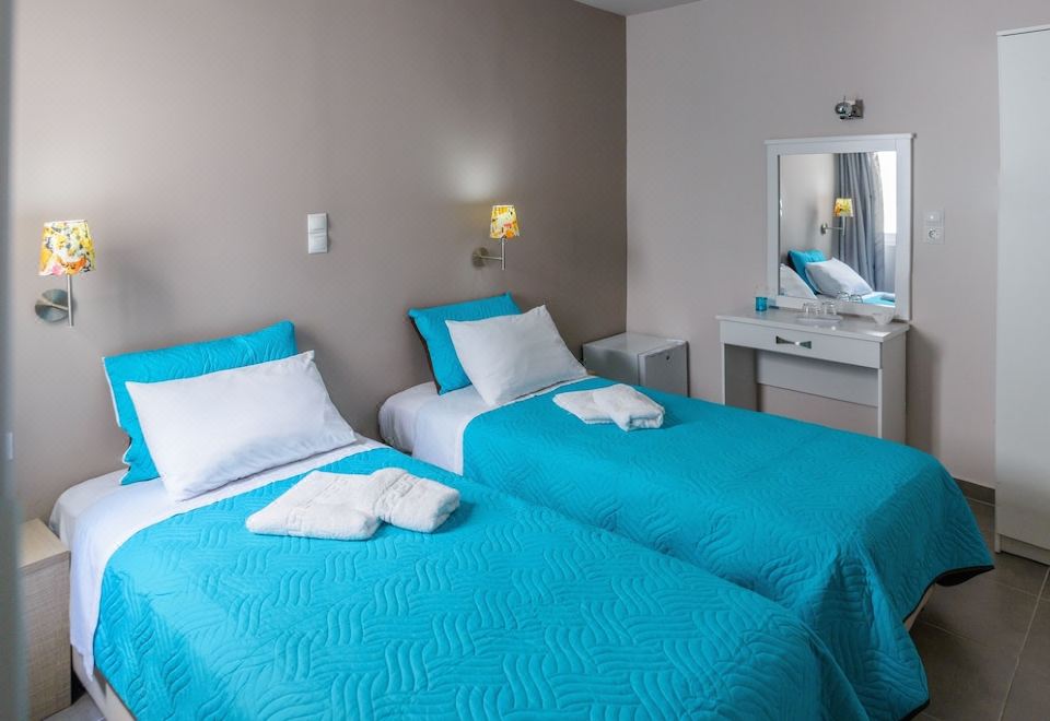a hotel room with two twin beds , a nightstand , and a mirror , all decorated in blue and white colors at Lux Hotel