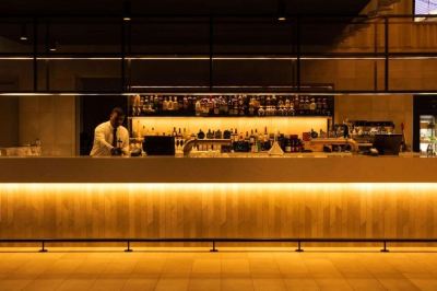 a man is standing behind a bar , preparing drinks for customers while illuminated by yellow lights at Oval Hotel at Adelaide Oval, an EVT hotel