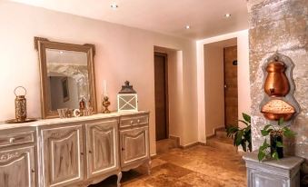 a room with a white cabinet , a wooden door , and a marble floor , featuring a potted plant and a mirror at La Bastide