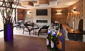 a bar area with multiple bottles of beer on the counter , along with several chairs and couches in the background at The Hide London