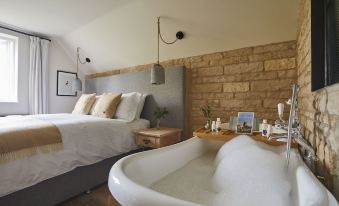 a bedroom with a large bed and a bathtub in the corner , creating a unique and cozy atmosphere at Wild Thyme & Honey