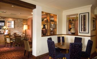 a dining room with a wooden table , chairs , and a vase on the wall behind the table at Premier Inn Tamworth South