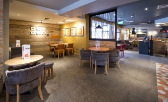 a large dining room with multiple tables and chairs arranged for a group of people to enjoy a meal together at Premier Inn Ware