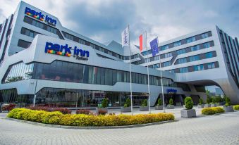 "a modern building with the name "" park inn "" on it , surrounded by trees and greenery" at Park Inn by Radisson Krakow