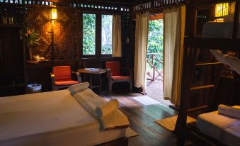 a cozy bedroom with a bed , two chairs , and a window with a view of trees at Our Jungle House