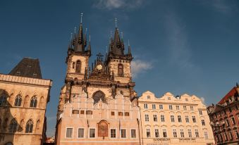 a grand , ornate church with two tall spires and a clock on the front of the building , standing in front of a building with white walls at Pure White