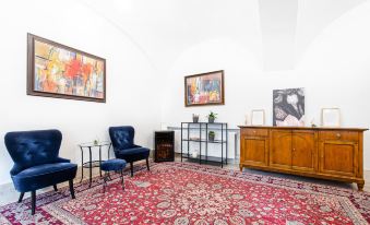 a cozy living room with a blue chair , a red rug , and a painting on the wall at BlueBell Hotel
