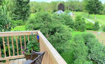 a wooden deck with a view of a lush green field and a house in the distance at Micosta Leisure Inn