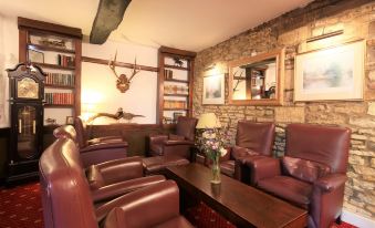 a cozy living room with leather chairs arranged around a coffee table , creating a comfortable and inviting atmosphere at The Crown Hotel