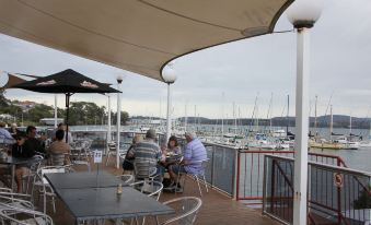 a group of people are sitting at a table on a deck overlooking the water at Beauty Point Waterfront Hotel