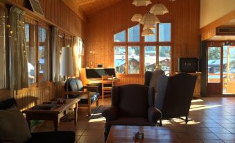 a cozy living room with wooden walls , large windows , and comfortable furniture , including a couch , chairs , and a coffee table at Hotel Roc et Neige