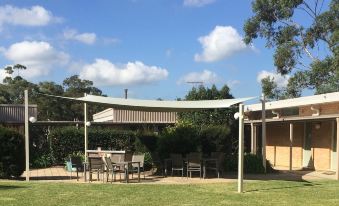 a white canopy hanging over a grassy area with a table and chairs set up for outdoor dining at Lucas Heights Motel