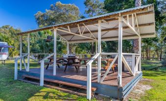 a wooden gazebo with a white roof and blue metal railing , surrounded by trees and grass at Ingenia Holidays South West Rocks