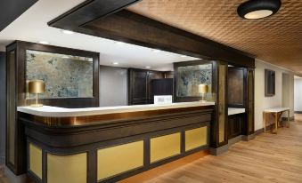 a modern hotel lobby with a wooden reception desk and a large painting on the wall at The Terrace Hotel Lakeland, Tapestry Collection by Hilton