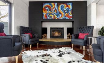 a cozy living room with two black couches , a fireplace , and a rug on the floor at Berry Village Boutique Motel