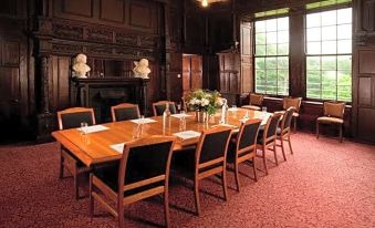 a large wooden conference table surrounded by chairs in a room with red carpeting and a fireplace at The Old Lodge