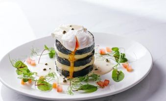 a white plate with a layer of cake on it , topped with a poached egg at Loftsome Bridge Hotel