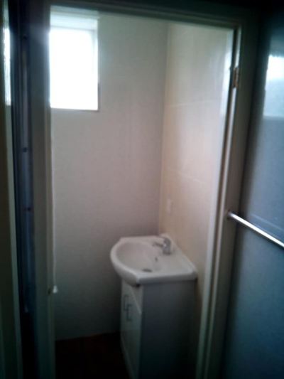 a small bathroom with a white sink and toilet , located next to a window with blinds at Moon Face