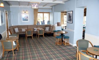 "a restaurant with blue walls , wooden tables , and chairs , and a plaid carpeted floor , under the name "" tonna" at Ferry House Inn