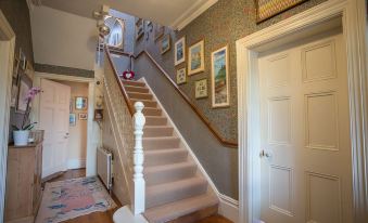 a staircase with a white railing and wooden steps leads up to a wall adorned with framed pictures at Clarendon