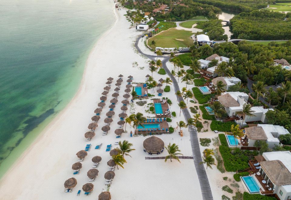 aerial view of a sandy beach with umbrellas , chairs , and other beach equipment scattered throughout at Fairmont Mayakoba