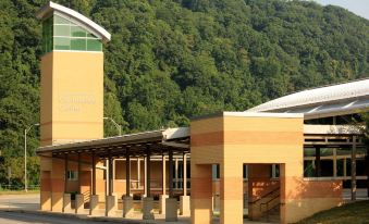 a modern building with a yellow exterior and a green awning is surrounded by trees at Holiday Inn Johnstown-Downtown