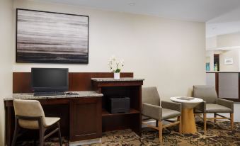 a desk with a laptop and a vase of flowers in the corner of a room at Residence Inn Boston Foxborough
