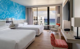 a modern hotel room with two beds , a desk , and a balcony offering a view of the ocean at Curacao Marriott Beach Resort