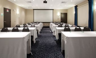 a large conference room with multiple tables and chairs , a screen , and a blue carpet at Holiday Inn Hammond