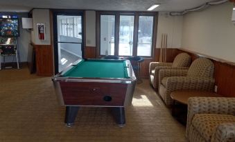 a pool table is in the middle of a room with a chair and couches at Pinestead Reef Resort