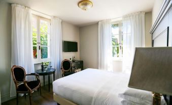 a large , white bed with a wooden headboard is in the center of a room with two windows at Hotel Vannucci