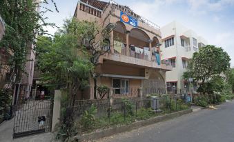 a two - story building with a balcony on the first floor , surrounded by trees and a dirt road at Radical