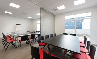 a conference room with black tables and red chairs , large windows , and a projector screen at K Hotel