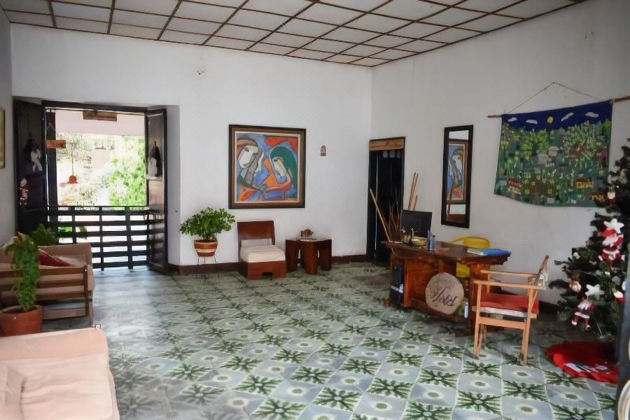 a spacious living room with a tiled floor , white walls , and various pieces of furniture such as a dining table , chairs , and a at Hotel San Cristobal