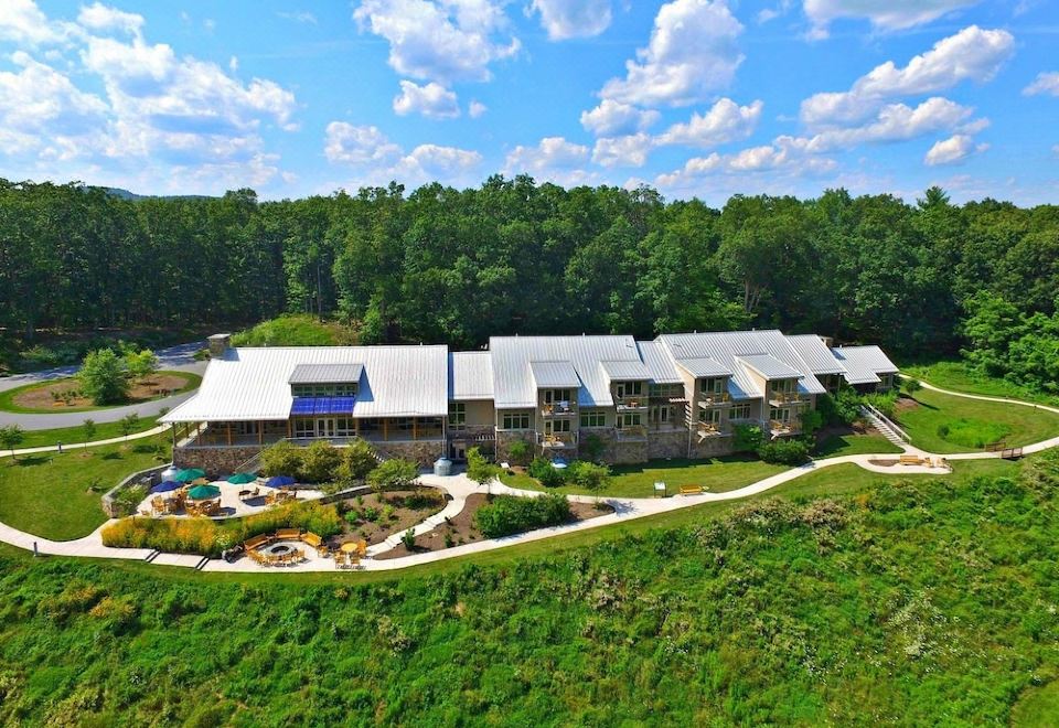 aerial view of a large stone building surrounded by trees and grass , with a parking lot in front at Nature Inn at Bald Eagle