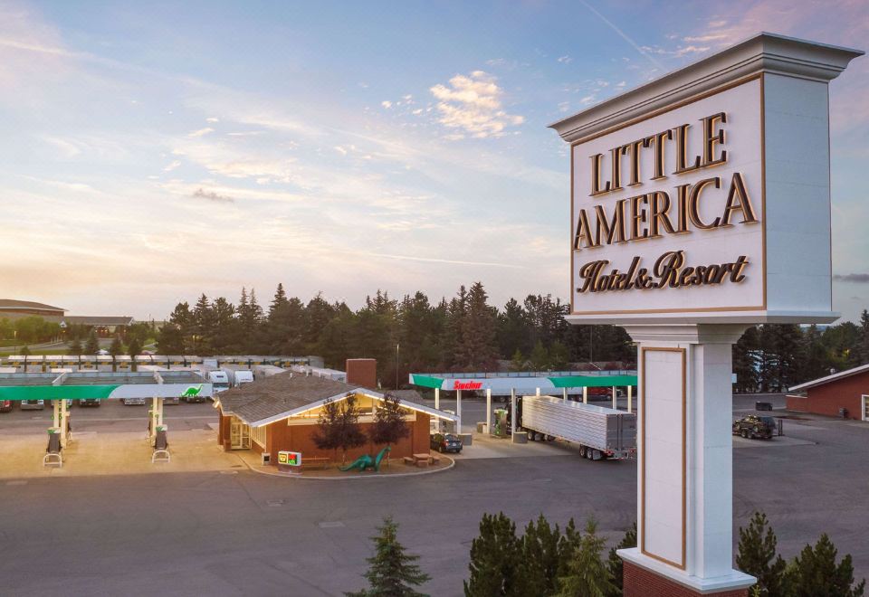 "a large sign for "" little america "" hotel and restaurant , situated in a parking lot surrounded by trees" at Little America Hotel & Resort Cheyenne