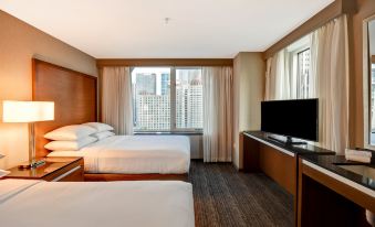 a hotel room with two beds , a window , and a tv , giving it a cozy and comfortable feel at Embassy Suites by Hilton Chicago Downtown Magnificent Mile