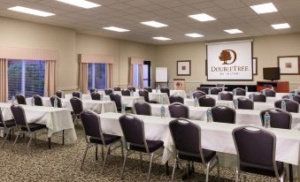 a large conference room with rows of chairs arranged in a semicircle , and a projector screen on the wall at DoubleTree by Hilton Portland - Tigard