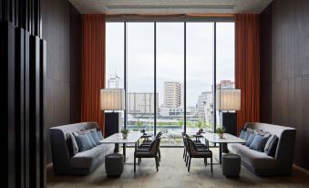 There is a room with large windows, chairs around a table, and an area rug covering the floor at Hyatt Centric Kanazawa