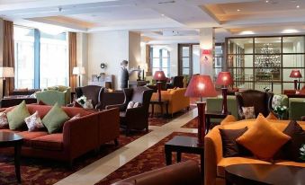 a hotel lobby with several couches , chairs , and tables arranged in a comfortable and inviting atmosphere at The Savoy Hotel