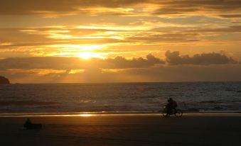 a person is riding a bicycle on the beach at sunset , with the sun setting behind the horizon at Conchal Hotel