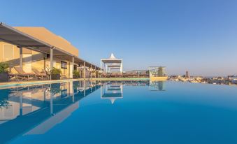 a large swimming pool is surrounded by a building and has a white structure in the background at AX The Palace