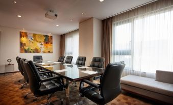 a conference room with a glass table surrounded by black chairs and a large window at Lotte City Hotel Ulsan