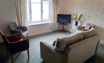 a living room with a couch , chair , and television is shown next to a window at Ferry House Inn