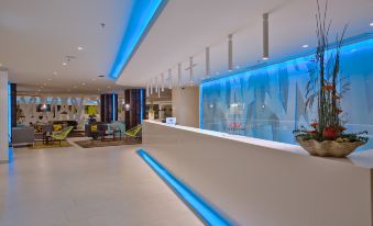 a modern hotel lobby with a blue and white color scheme , including a reception desk and a seating area at Park Plaza Belvedere Medulin