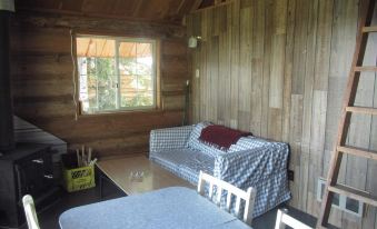 a cozy wooden cabin with a couch , table , and chairs in the living area , surrounded by windows at Pine Point Resort