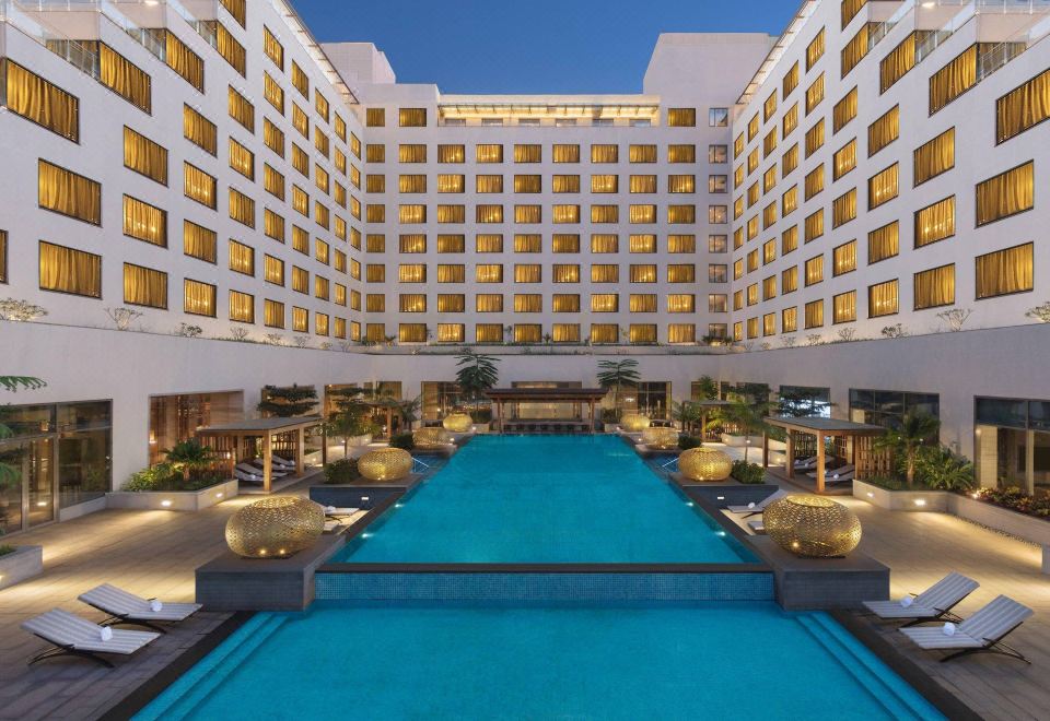 a large hotel with a pool surrounded by multiple buildings , creating a luxurious and modern atmosphere at Sheraton Grand Bengaluru Whitefield Hotel & Convention Center