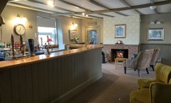 a modern , well - lit bar with wooden paneling and a large counter , surrounded by comfortable seating and a fireplace at The Red Lion Inn